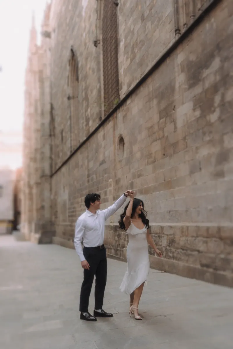 Couple dancing joyfully along a historic stone street during a couples & engagements photoshoot.
