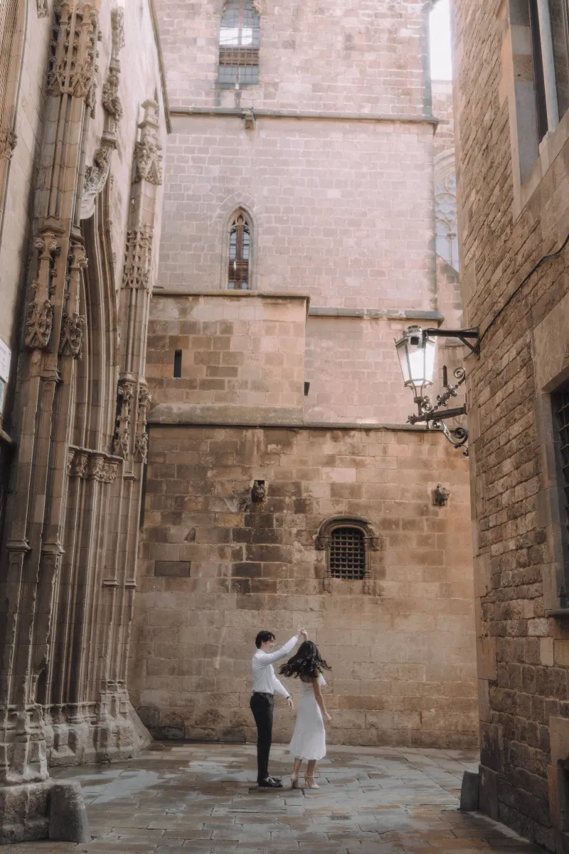 Couple dancing together in a quiet Gothic Quarter alley, sharing a joyful moment during their engagement photoshoot.