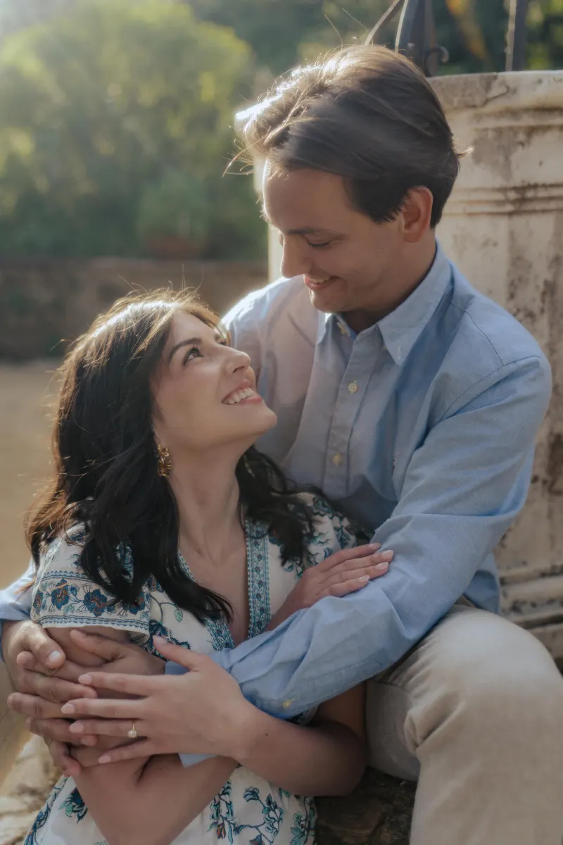 Couple embraces and shares a joyful gaze in golden sunlight during a Mediterranean surprise proposal photoshoot.
