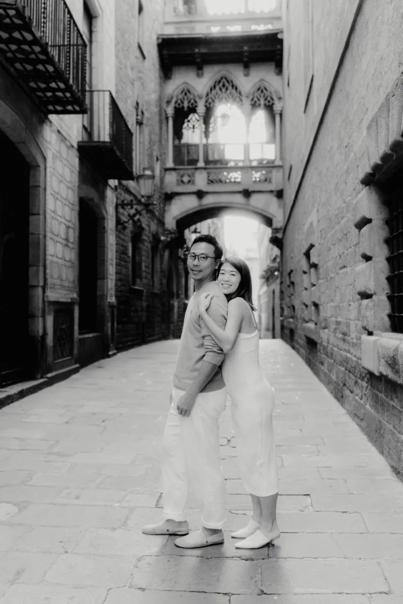 Couple embraces and smiles during a Vacation Portraits photoshoot in a quiet Gothic Quarter alley in Barcelona.