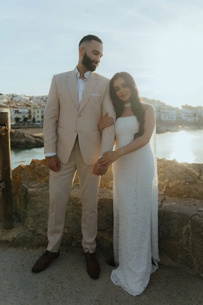 Couple embraces by the seaside at sunset during a surprise proposal photoshoot, radiating joy and love.