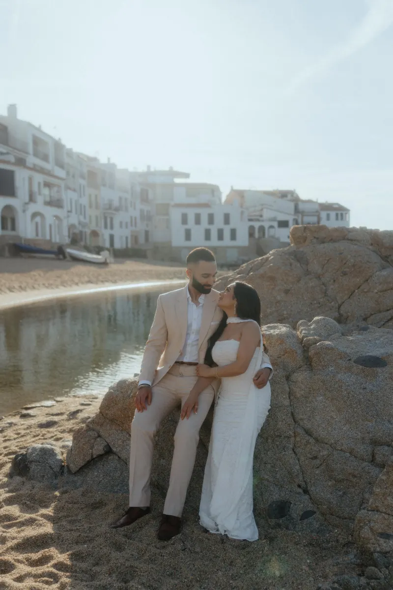 Couple embraces on a sunlit beach in Spain, sharing a joyful moment during a surprise proposal photoshoot.