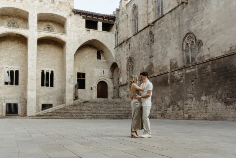 Couple embracing and smiling in a quiet Barcelona courtyard during their Vacation Portraits photoshoot.