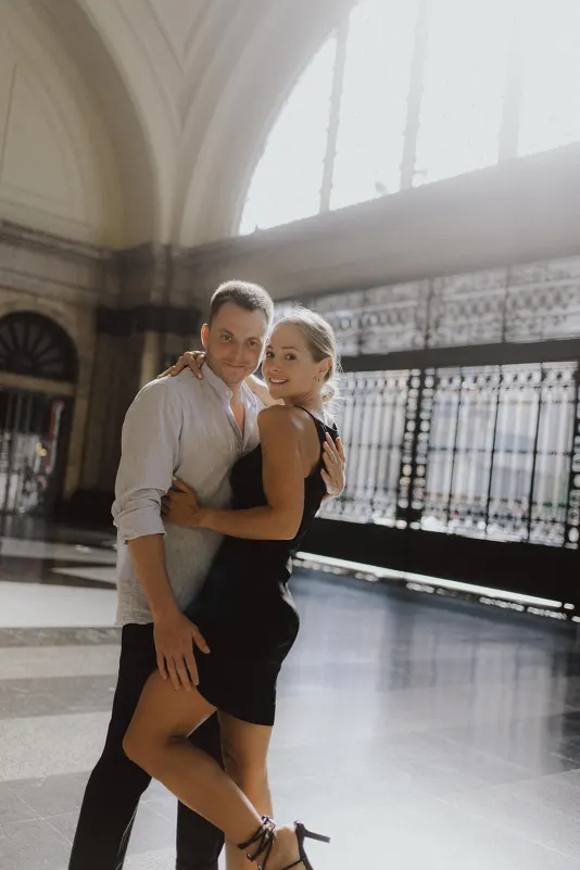 Couple embracing and smiling in a sunlit grand hall, captured during a couples & engagements photoshoot session.