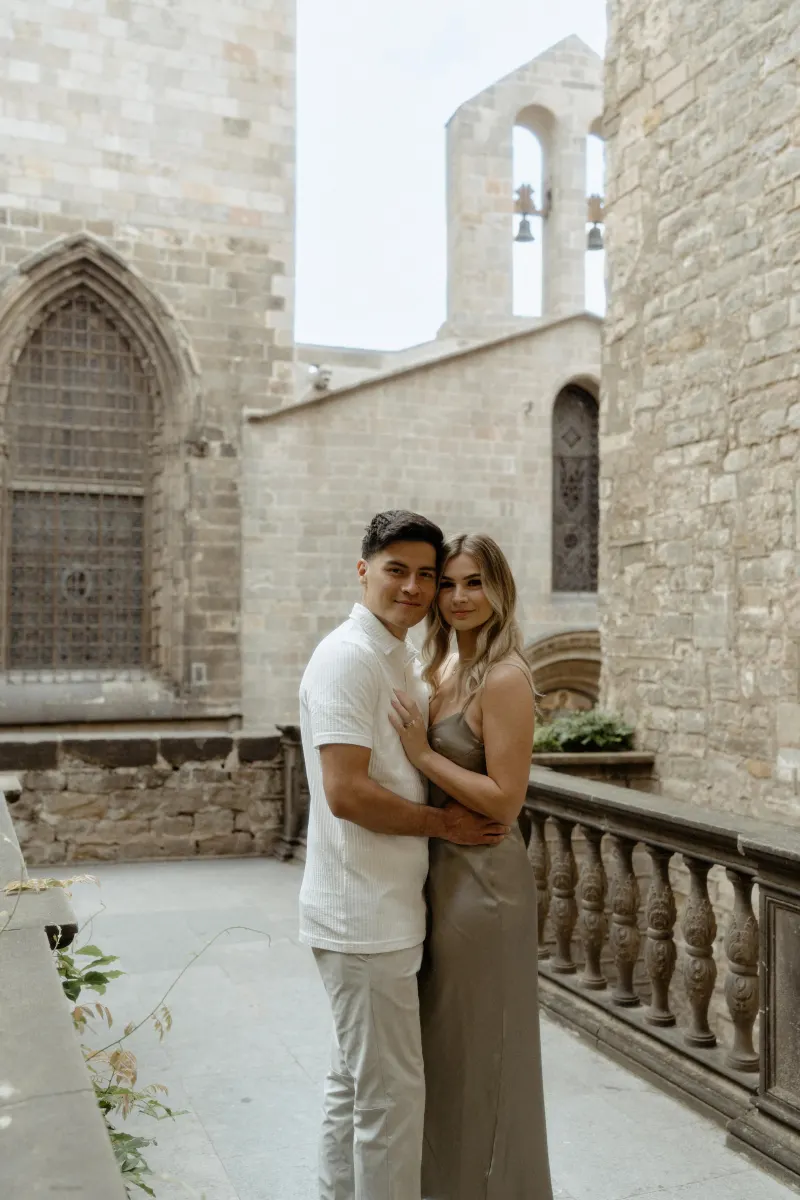 Couple embracing and smiling softly in a historic Barcelona courtyard during their Vacation Portraits photoshoot.