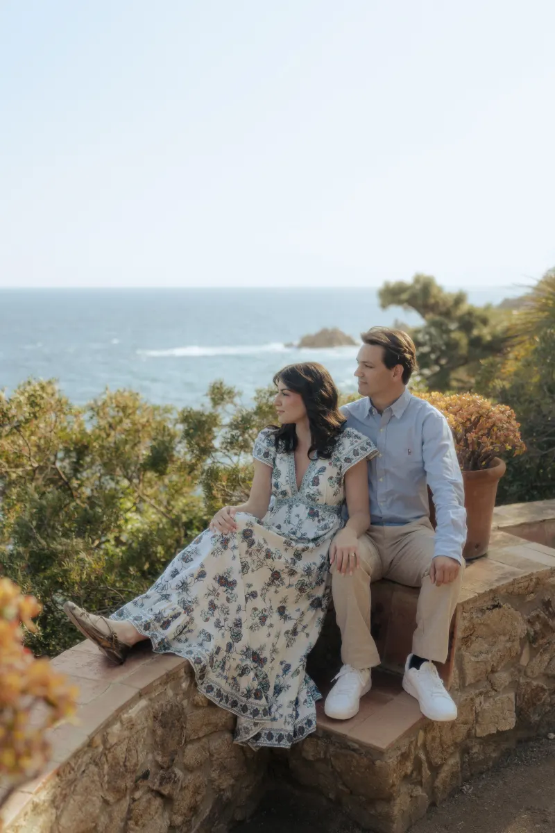 Couple enjoys a peaceful moment together on a stone terrace overlooking the sea during a surprise proposal photoshoot.