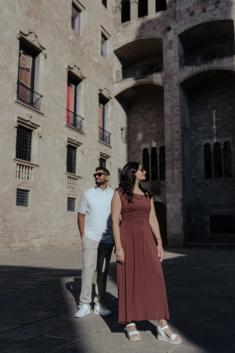 Couple enjoys a quiet moment together in soft sunlight during their engagement photoshoot in a historic city courtyard.