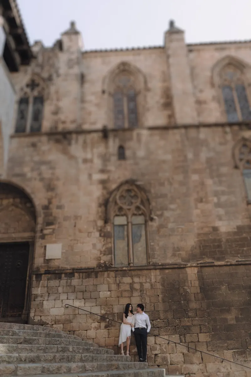 Couple gazes at each other on historic stone steps, sharing a quiet moment during their engagement photoshoot.