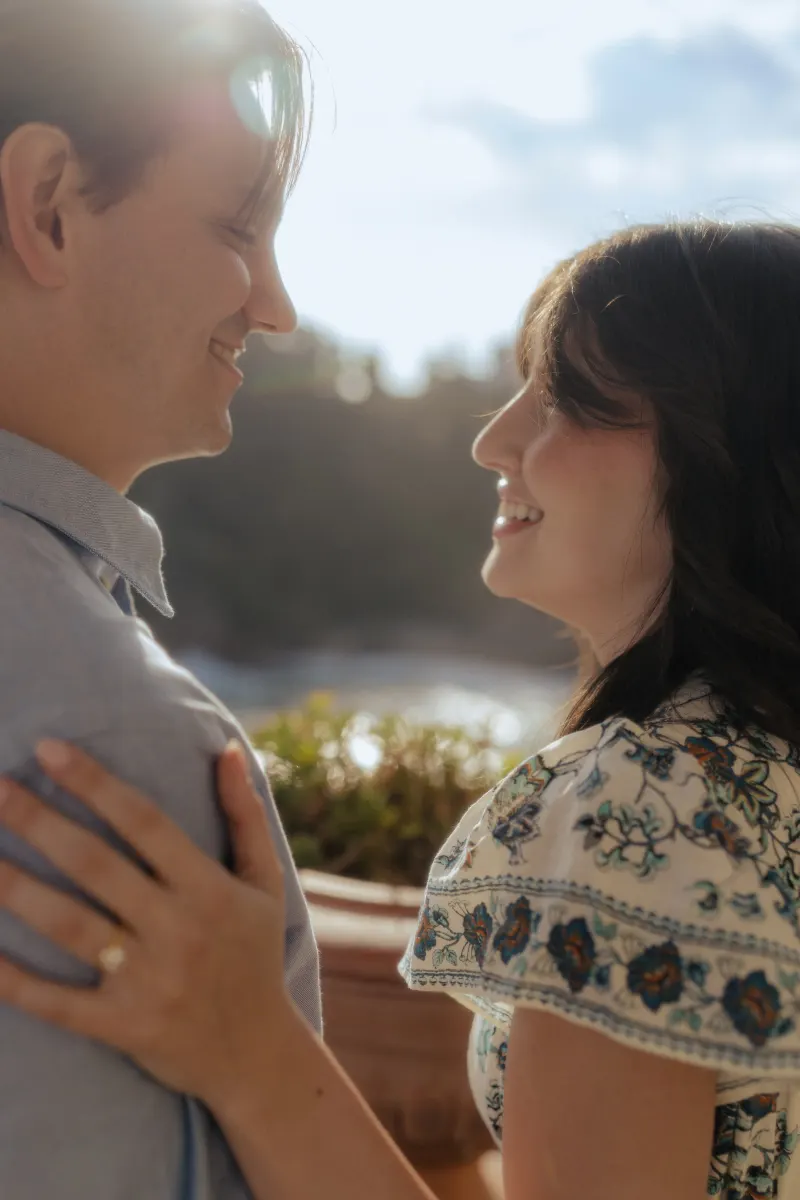 Couple gazes at each other, smiling warmly after a Mediterranean surprise proposal photography session.