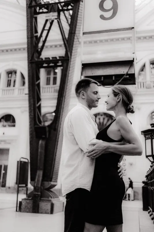 Couple gazing into each other's eyes at a grand train station, captured during a couples & engagements photoshoot.