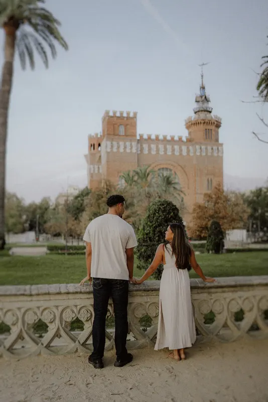 Couple holding hands and gazing at a historic castle, captured during a romantic couples & engagements photoshoot.