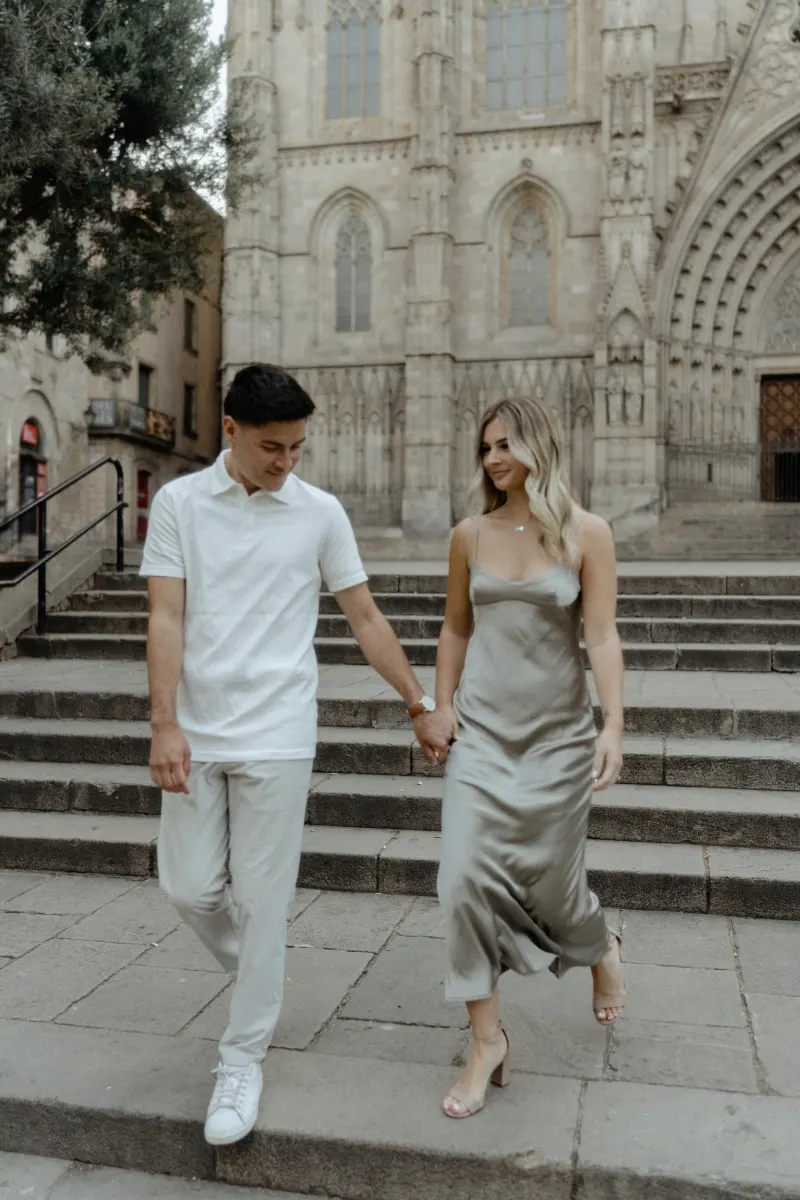 Couple holding hands and sharing a sweet moment on cathedral steps in Barcelona during a Vacation Portraits session.