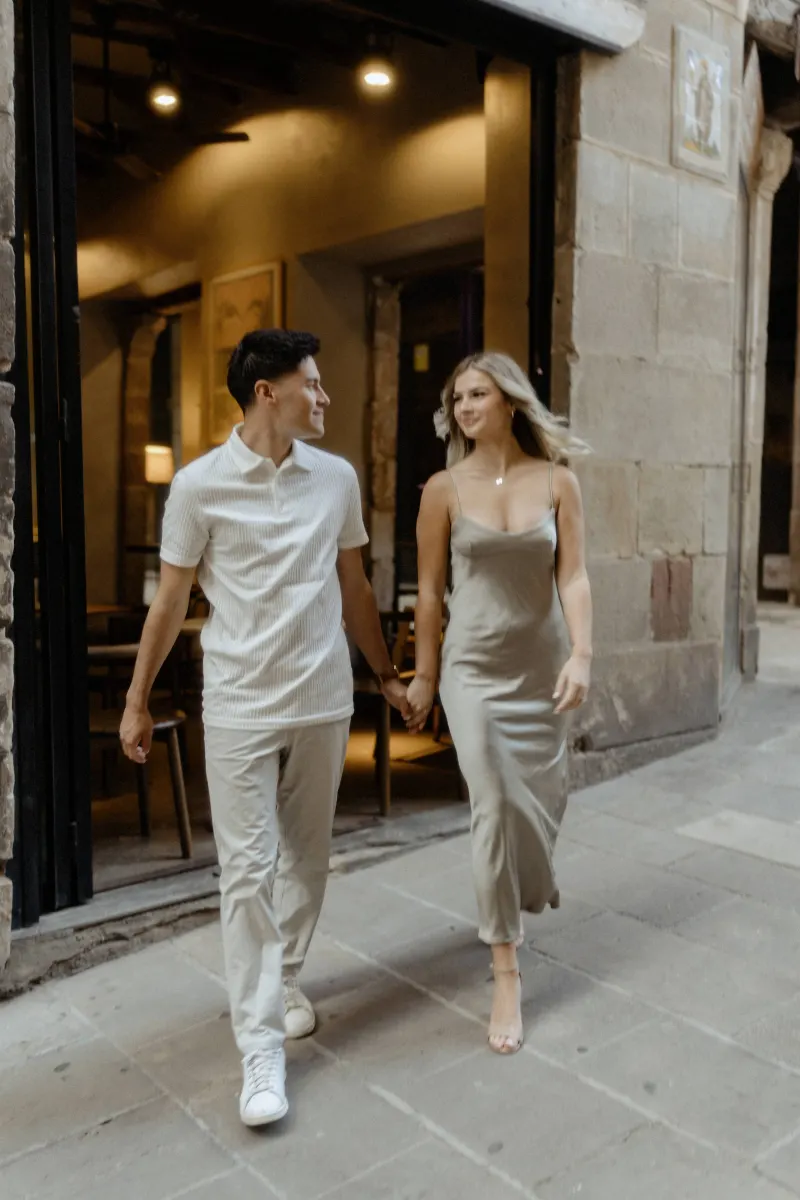 Couple holding hands and smiling as they leave a cozy Barcelona café, captured during a Vacation Portraits photoshoot.
