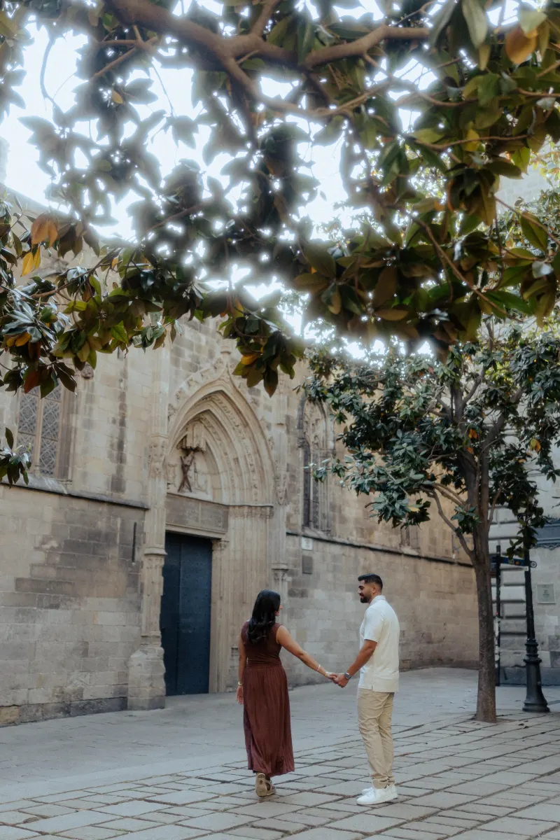Couple holding hands and smiling at each other during a couples & engagements photoshoot in a historic city courtyard.