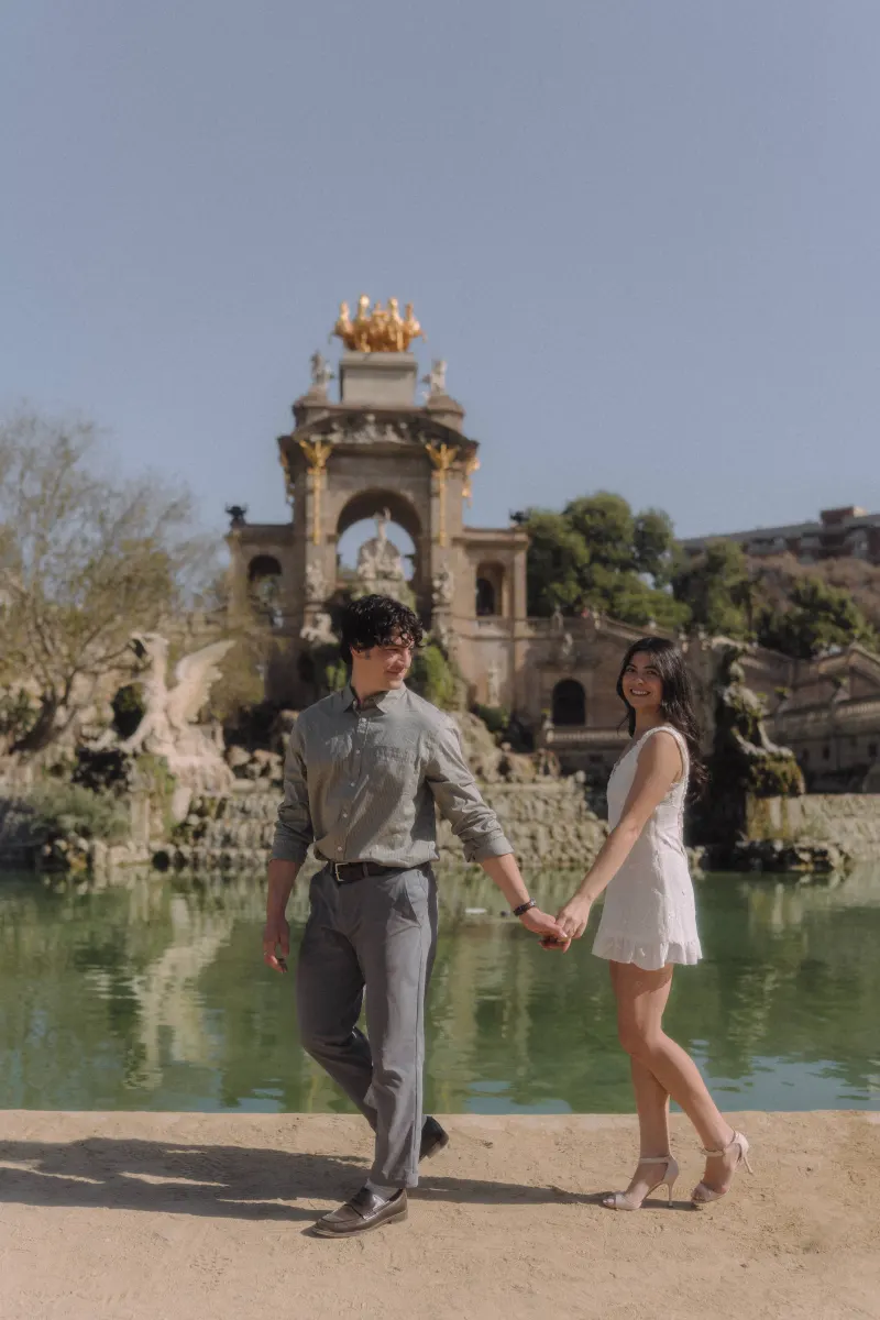 Couple holding hands and smiling by the fountain at Parc de la Ciutadella during a couples & engagements photoshoot.