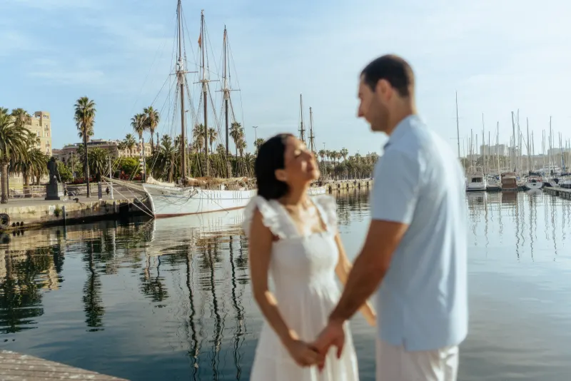 Couple holding hands and smiling softly by the marina, captured during a couples & engagements photoshoot session.