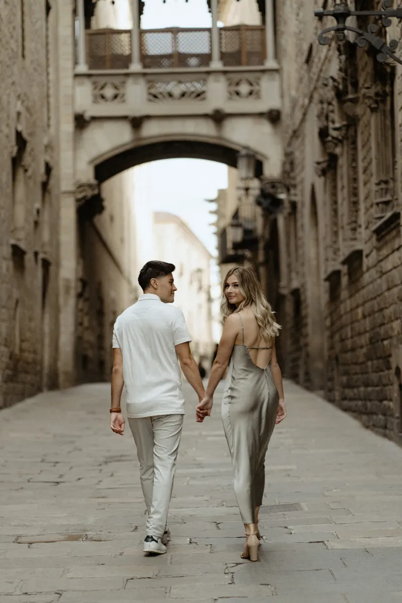 Couple holding hands and strolling through Barcelona’s Gothic Quarter, captured during a Vacation Portraits photoshoot.