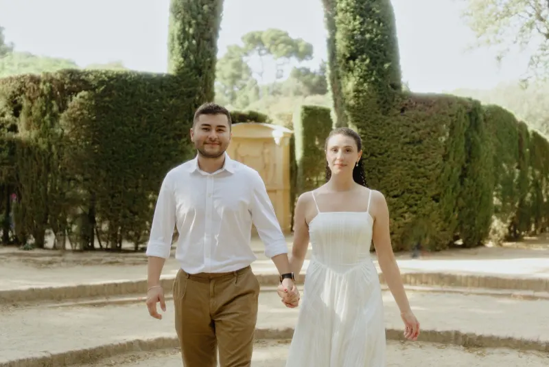Couple holding hands and walking through a sunlit garden, captured during a couples & engagements photography session.