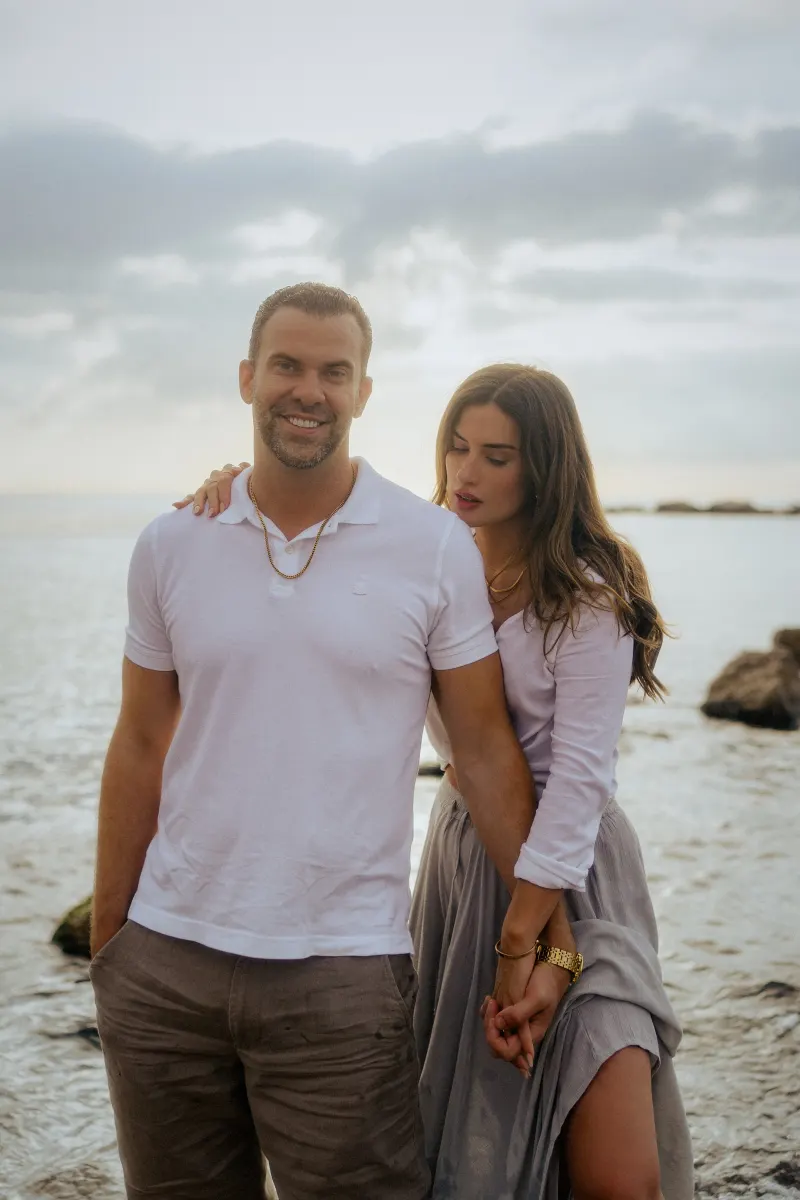 Couple holding hands by the sea, sharing a quiet, affectionate moment during a couples & engagements photoshoot.