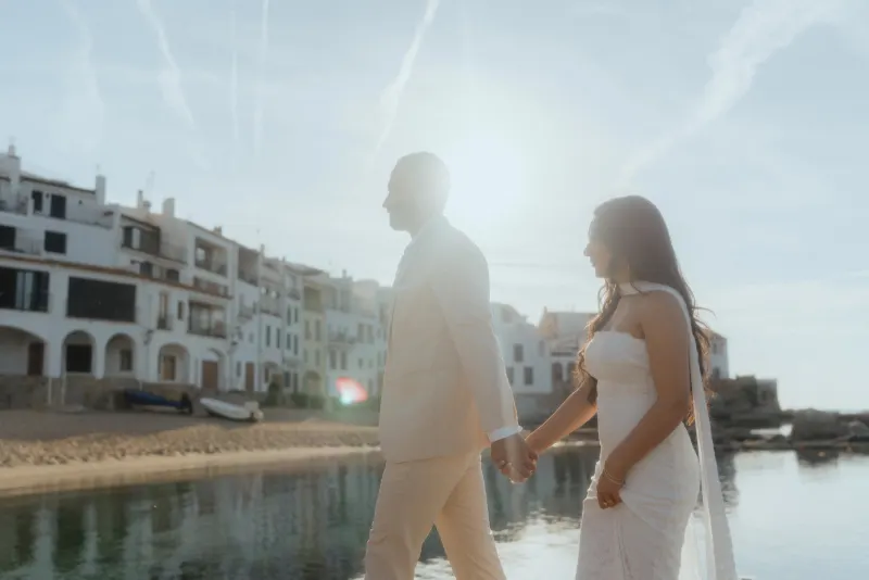 Couple holding hands by the waterfront at sunset during a surprise proposal photoshoot in a charming coastal village.