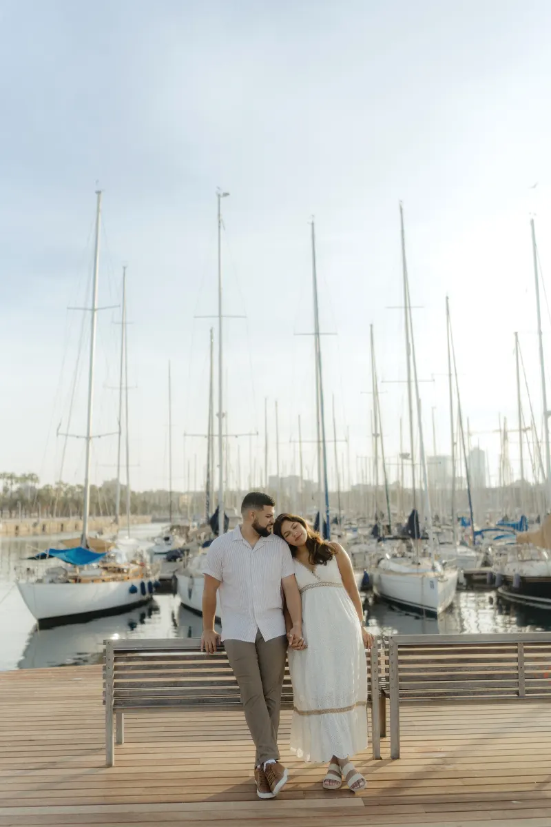 Couple holds hands and shares a tender moment on a marina boardwalk during a couples & engagements photoshoot.