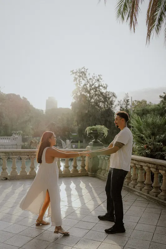 Couple laughing and dancing together on a sunlit terrace during a couples & engagements photoshoot at Parc de la Ciutadella.
