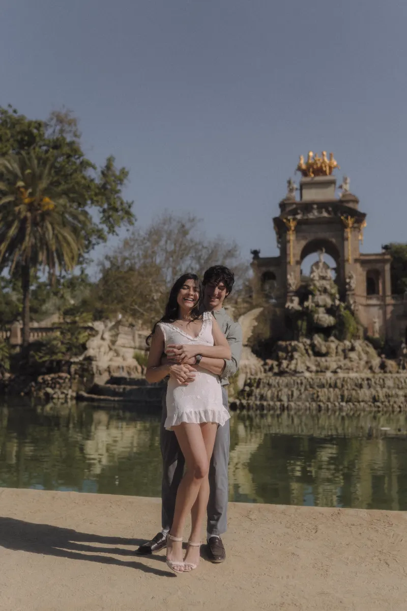 Couple laughing and embracing by the fountain at Parc de la Ciutadella during a joyful engagement photoshoot.