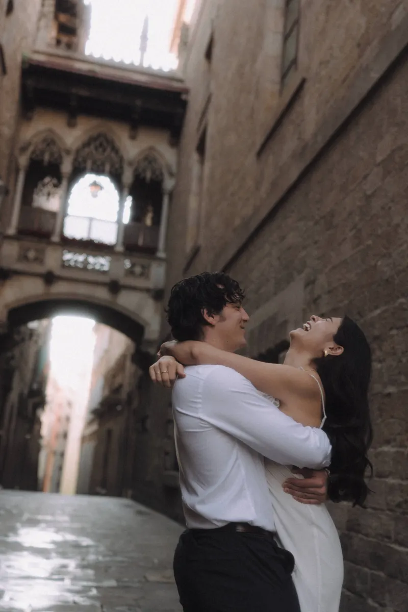 Couple laughing and embracing in a romantic Gothic Quarter alley during a couples & engagements photoshoot in Barcelona.
