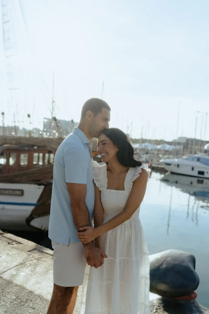 Couple laughing and holding hands on a marina dock, captured during a couples & engagements photoshoot.