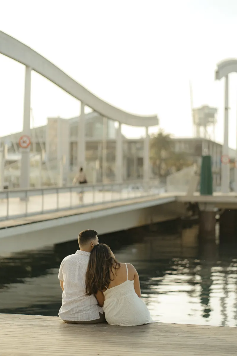 Couple leans together on a wooden dock, sharing a peaceful moment by the marina during their engagement photoshoot.