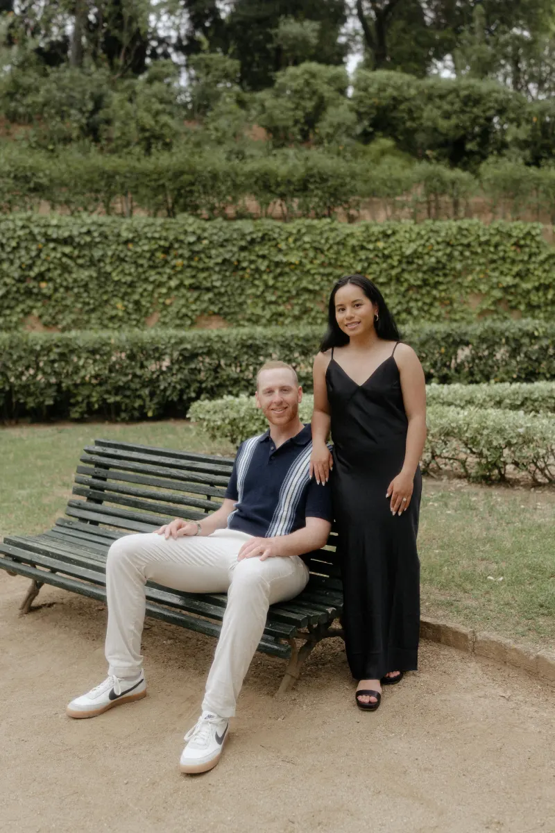 Couple poses together on a garden bench, sharing a relaxed moment during their surprise proposal photoshoot.