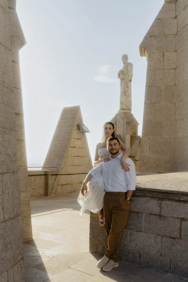 Couple poses together on sunlit stone terrace, sharing a relaxed moment during their couples & engagements photoshoot.