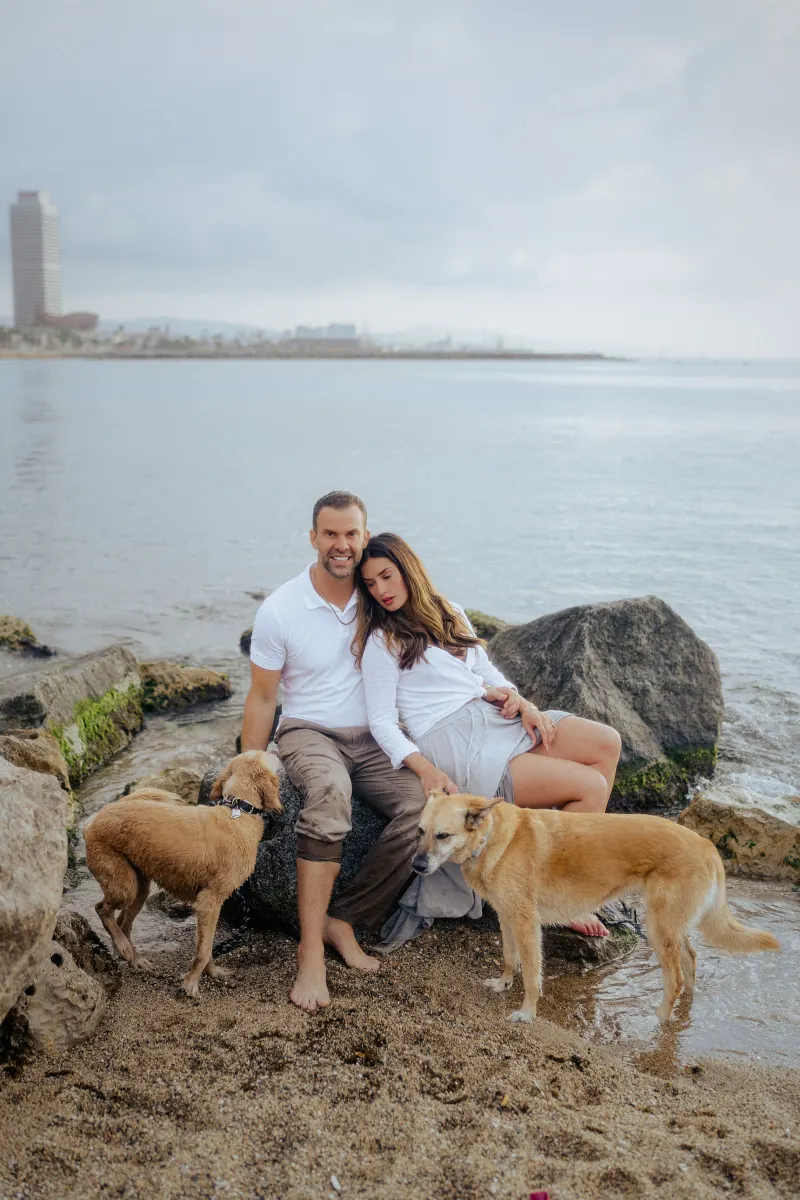 Couple relaxing together on seaside rocks with their two dogs, captured during a couples & engagements photoshoot.