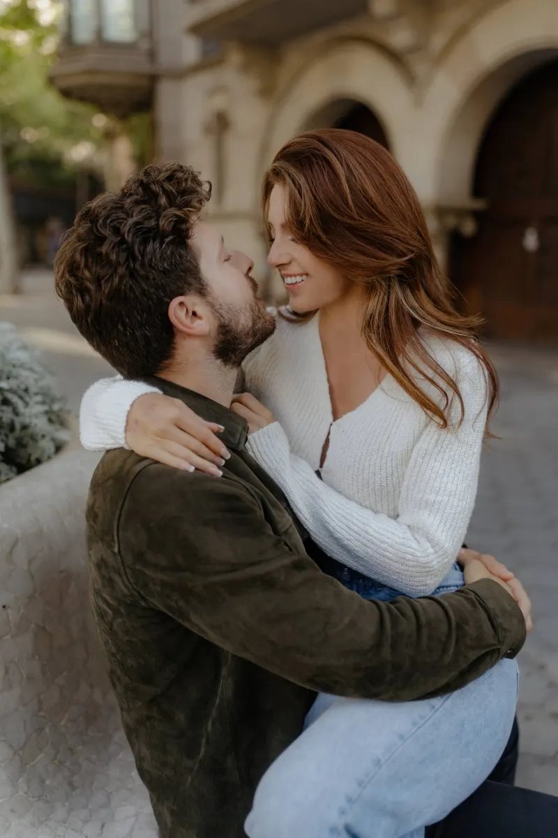 Couple shares a close, joyful embrace on a city bench during a couples & engagements photoshoot.