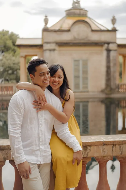Couple shares a happy embrace by a reflecting pool, captured during a couples & engagements photoshoot in the park.