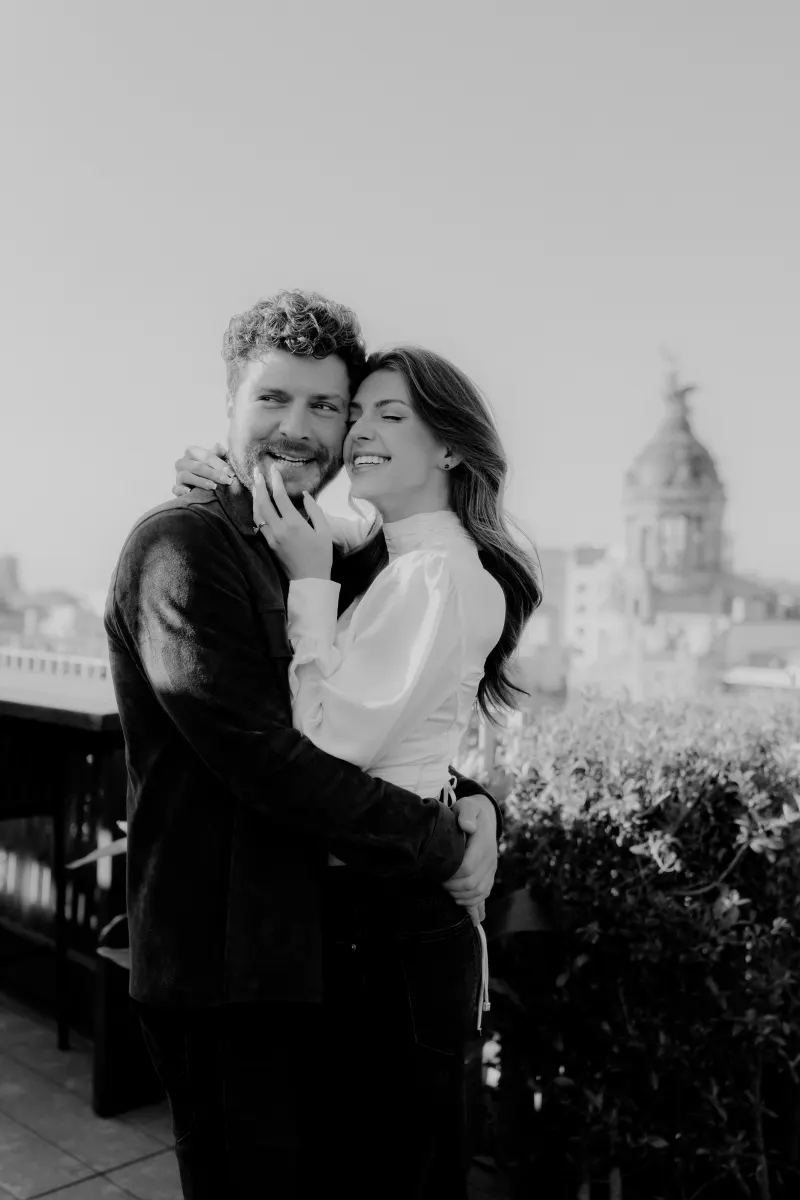Couple shares a heartfelt embrace and laughter on a rooftop, captured during a couples & engagements photoshoot in the city.