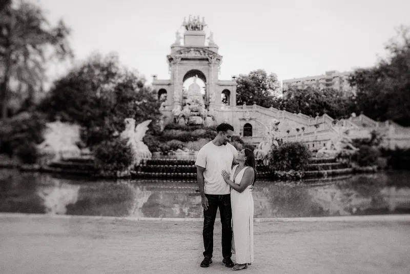 Couple shares a joyful embrace in front of the grand fountain at Parc de la Ciutadella during an engagement session.