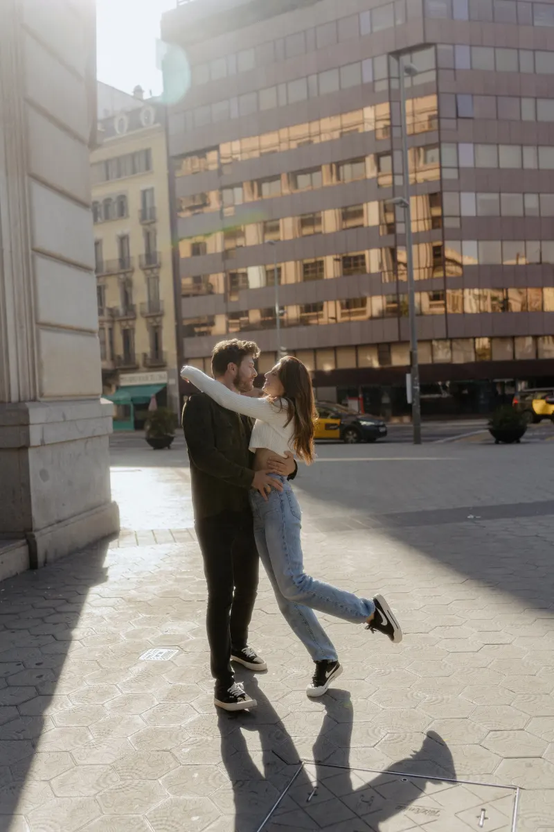 Couple shares a joyful embrace in the sunlight on a city street during a couples & engagements photoshoot.