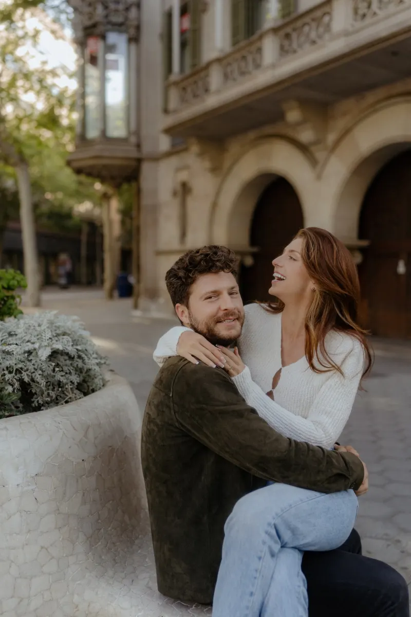 Couple shares a joyful embrace on a city street, laughing together during a couples & engagements photoshoot.