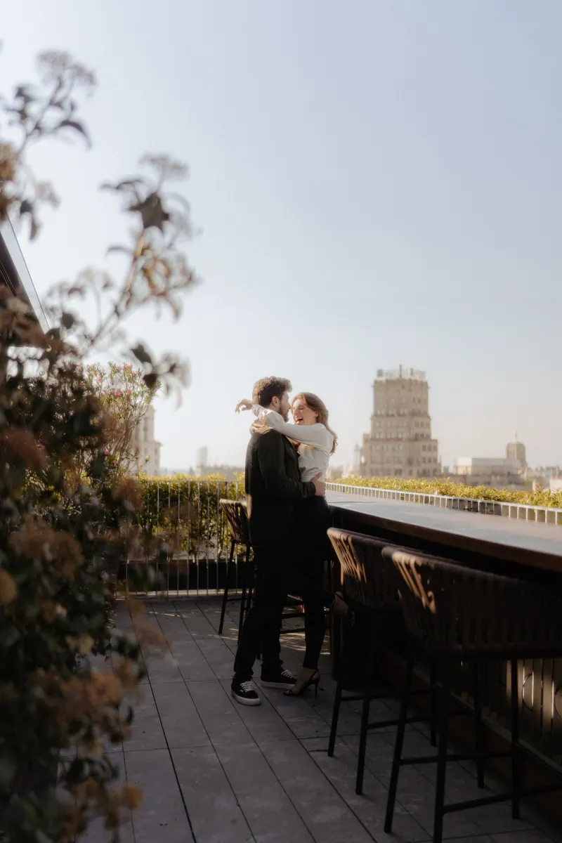 Couple shares a joyful embrace on a rooftop patio, captured during a couples & engagements photoshoot in the city.