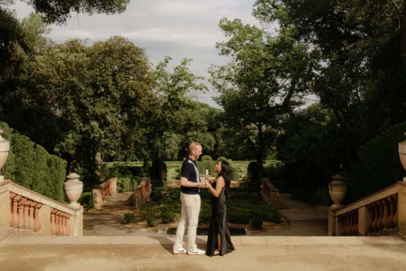 Couple shares a joyful, intimate moment on a garden terrace during a surprise proposal photoshoot.