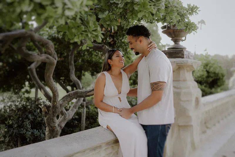 Couple shares a joyful, intimate moment on a garden terrace during their engagement photoshoot session.