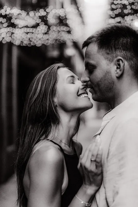 Couple shares a joyful, intimate moment under city lights during a couples & engagements photoshoot.
