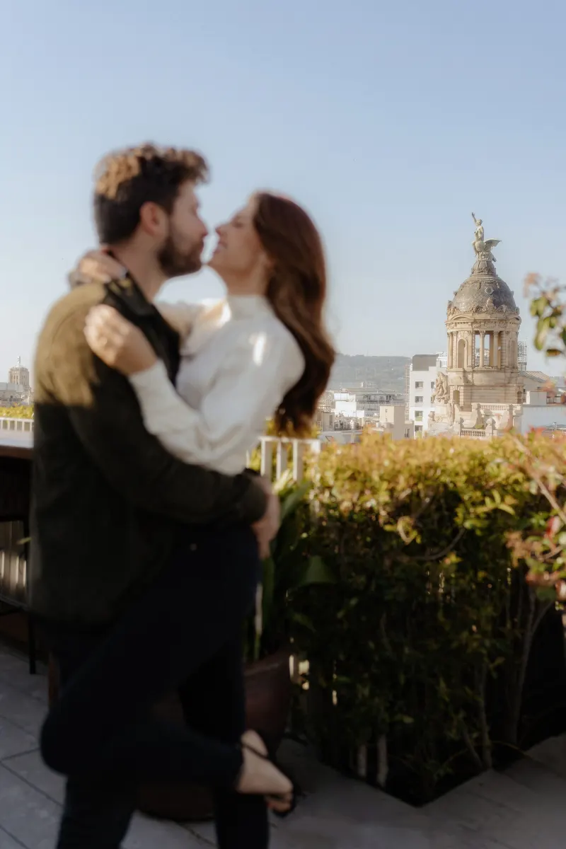 Couple shares a joyful lift and embrace on a sunlit rooftop, captured during a couples & engagements photoshoot in the city.
