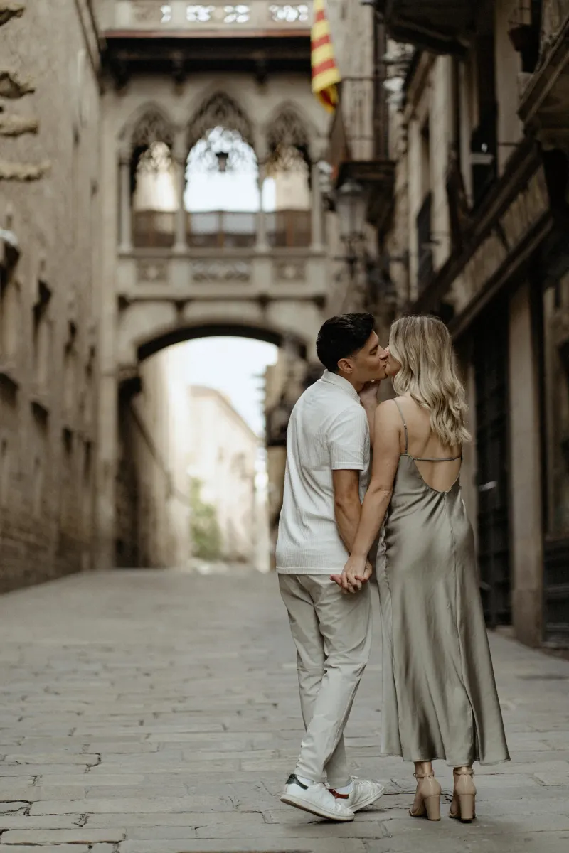 Couple shares a kiss while holding hands in Barcelona’s Gothic Quarter during a Vacation Portraits photoshoot.