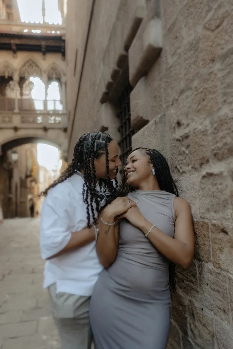 Couple shares a loving, candid moment against a stone wall in Barcelona’s Gothic Quarter during a surprise proposal session.