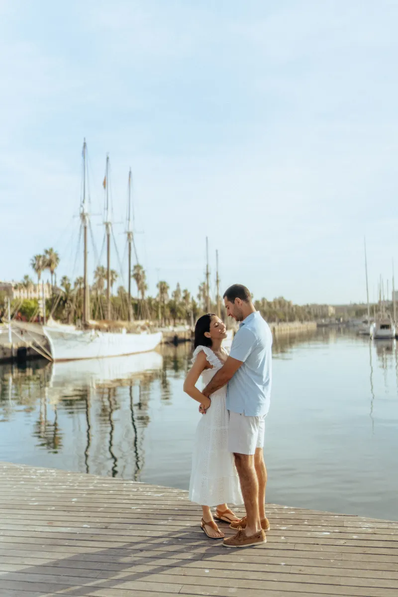 Couple shares a loving embrace on a sunlit marina dock, captured during a couples & engagements photoshoot session.