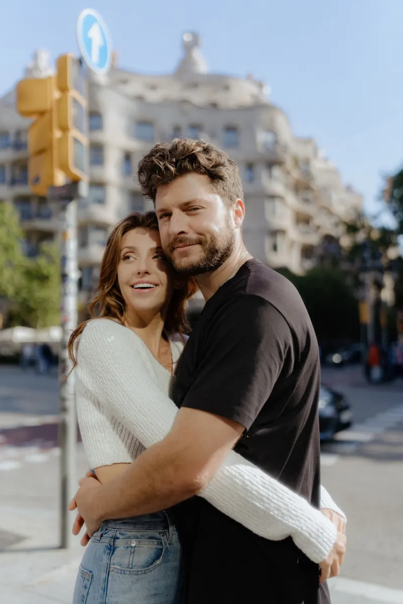 Couple shares a loving embrace on a sunny city street during a couples & engagements photoshoot.