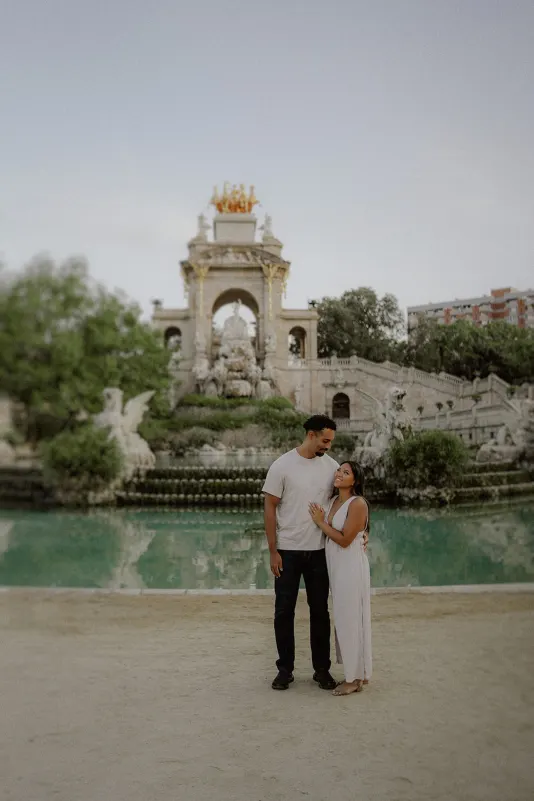 Couple shares a loving gaze by a grand fountain during an engagement photoshoot at Parc de la Ciutadella.