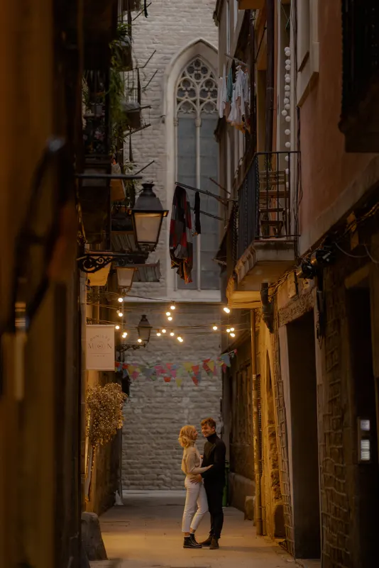 Couple shares a loving gaze in a lantern-lit Barcelona alley during a couples & engagements photoshoot.